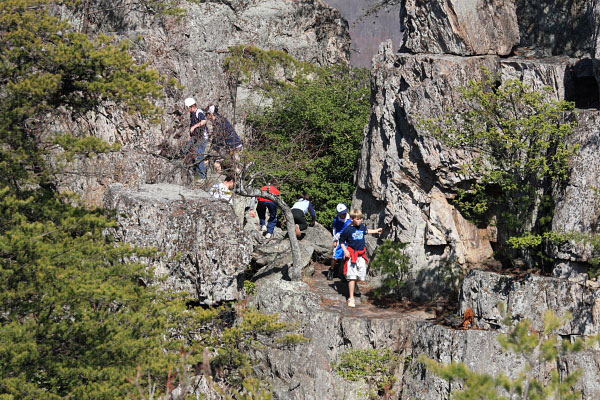 Photo of a crowd of kids making their way over the large boulders on the mountain-top 